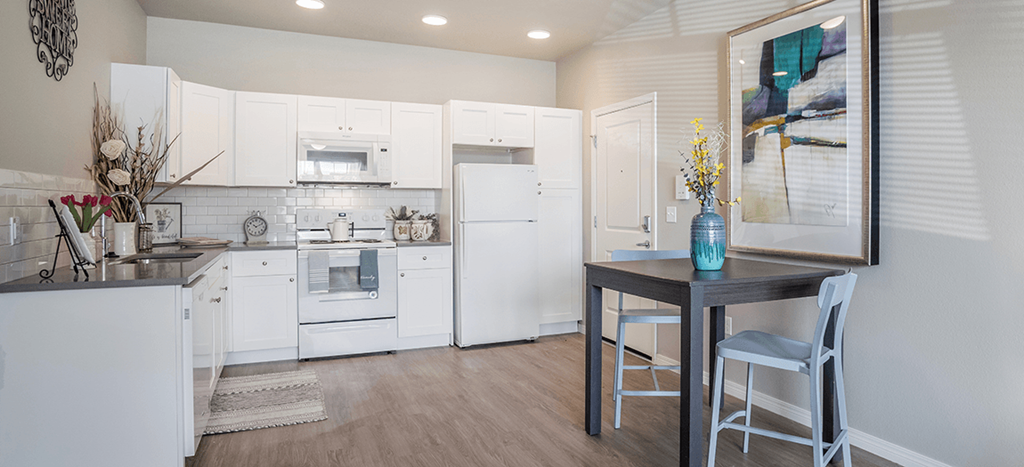 a kitchen with white appliances and a table with chairs at West Park Apartments