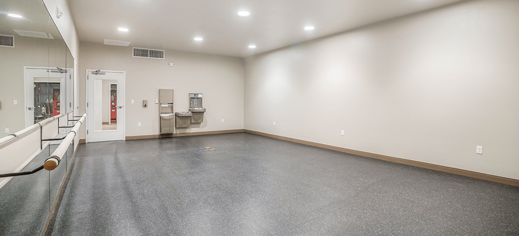 an empty yoga room with white walls and a mirrored wall with a ballet bar