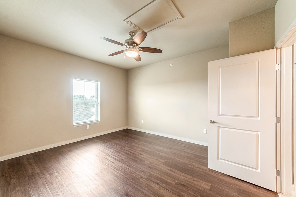 an empty living room with a ceiling fan and a door