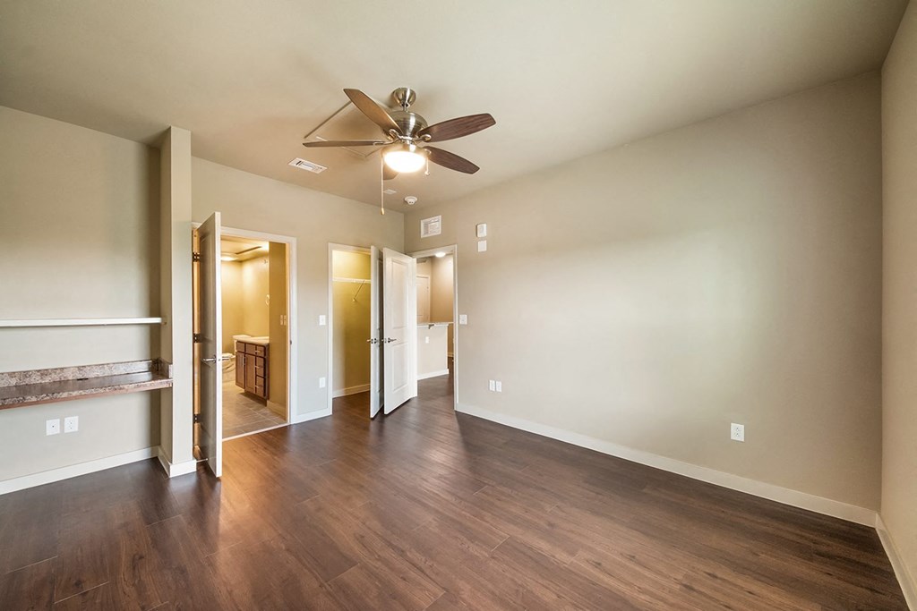 a empty living room with a ceiling fan and wood floors