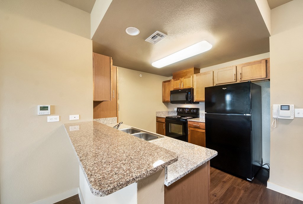 a kitchen with granite countertops and a black refrigerator