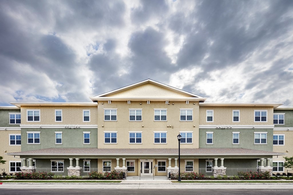 a large apartment building on a street with a cloudy sky