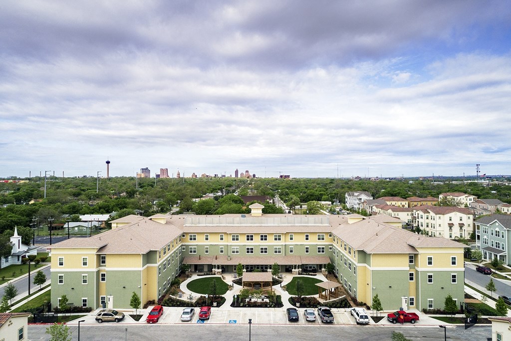 an aerial view of a building with a parking lot and a city in the background