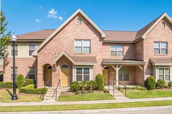 A brick house with a brown door and windows.