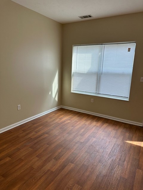an empty living room with wood floors and a window