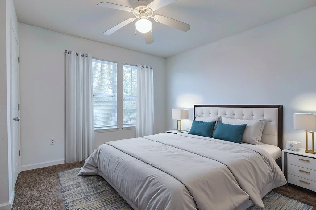 A bedroom with a large bed and a ceiling fan.