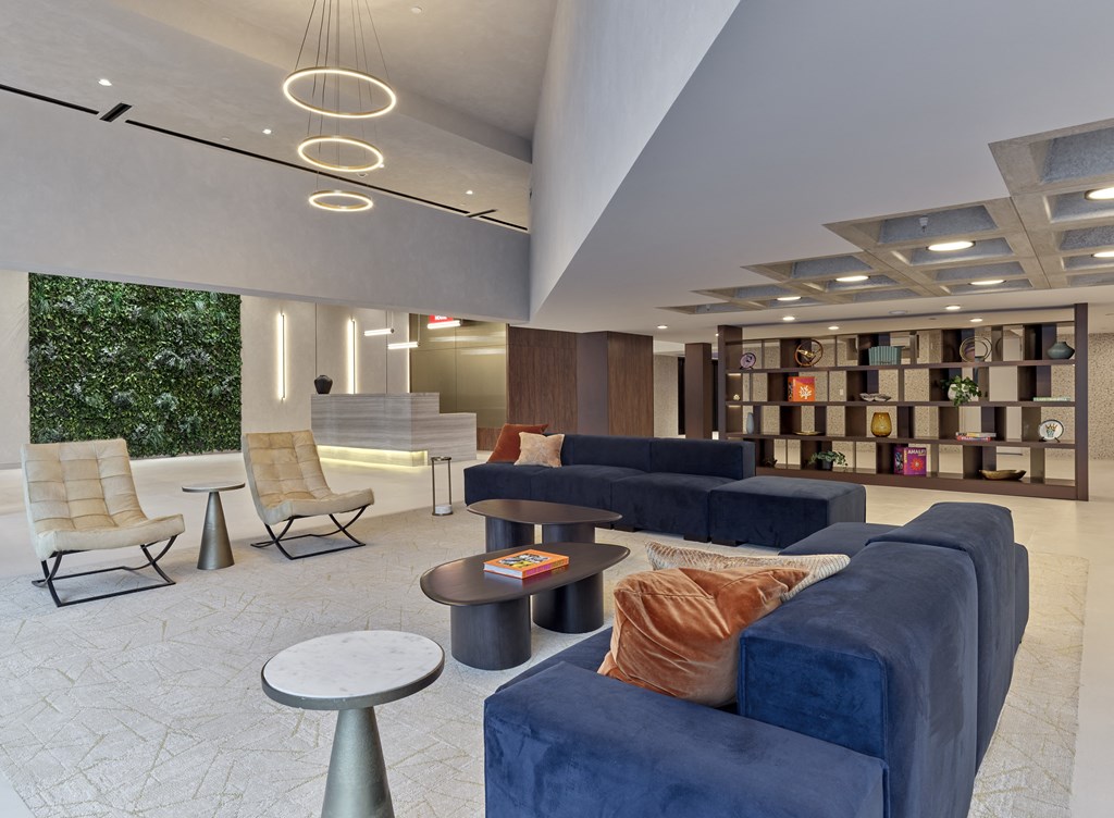 a lobby with blue couches and chairs and a bookshelf