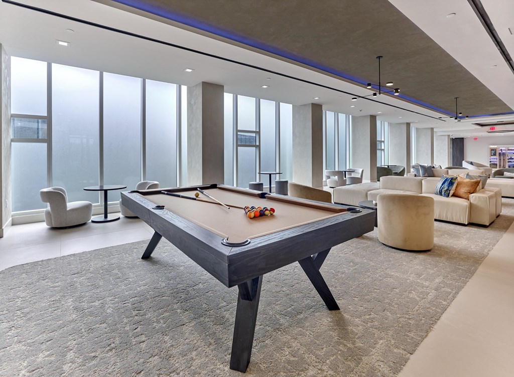 A pool table in a room with a carpeted floor and a large window.