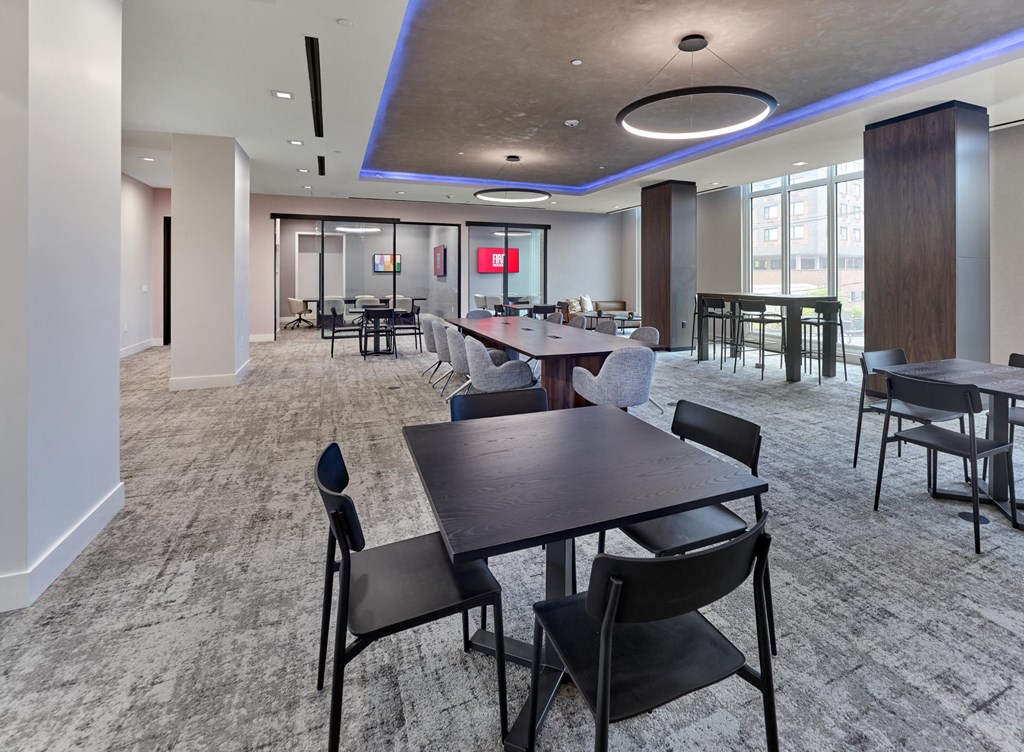 A large room with tables and chairs and a red screen.