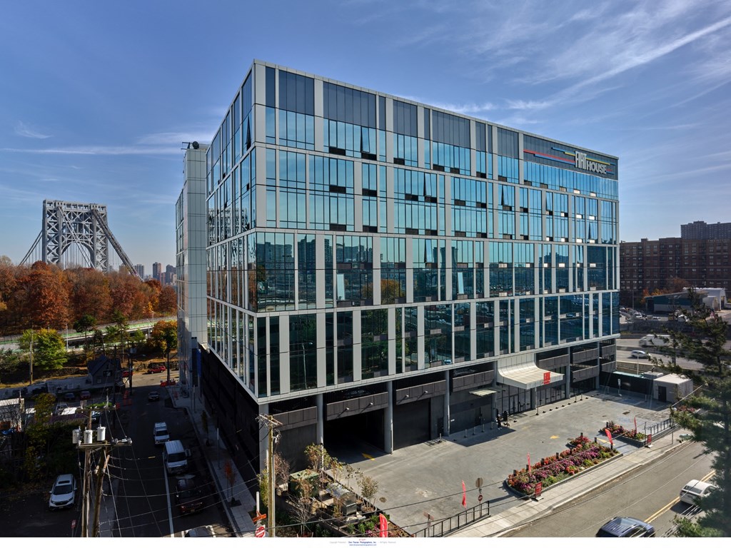 A modern glass building with a bridge in the background.