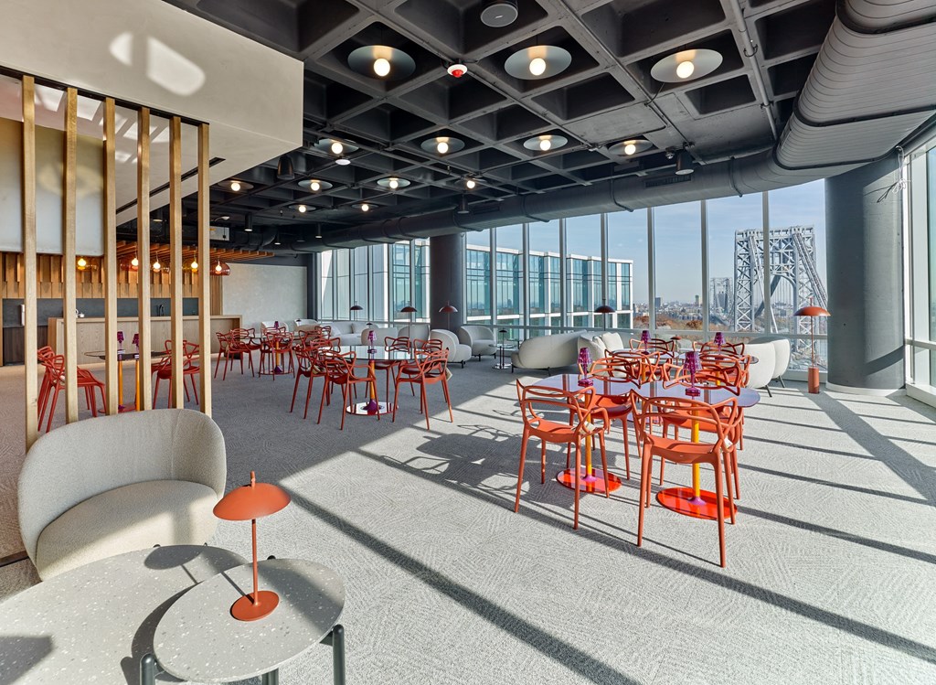 A room with tables and chairs and a view of the city.