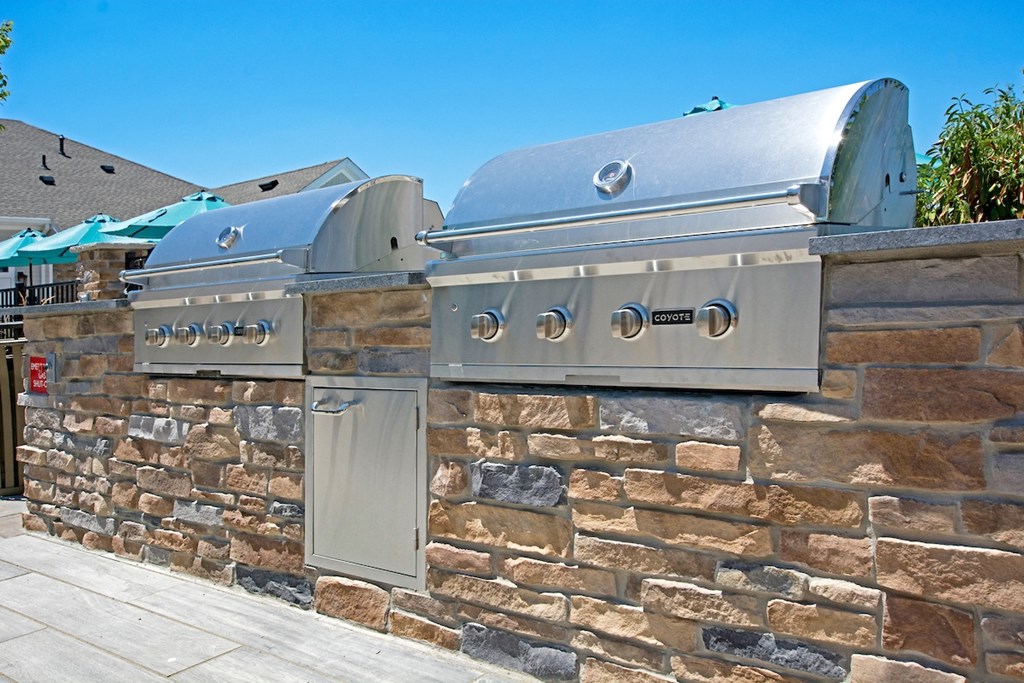 an outdoor kitchen with stainless steel appliances and a stone wall