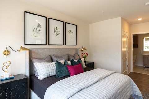 A bedroom with a bed, nightstand, and three framed pictures on the wall.