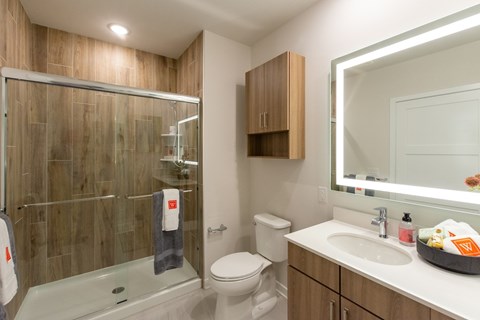 A bathroom with a white toilet, a sink, a mirror, and a glass shower stall.
