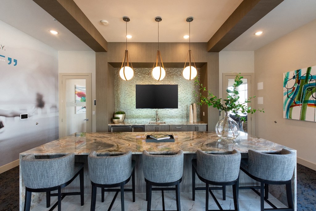 a kitchen with a large island with a marble countertop and a tv in the background