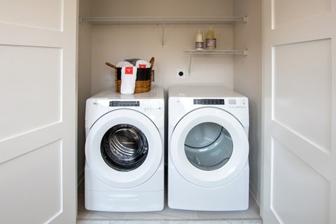 Two white front load washing machines in a small laundry room.
