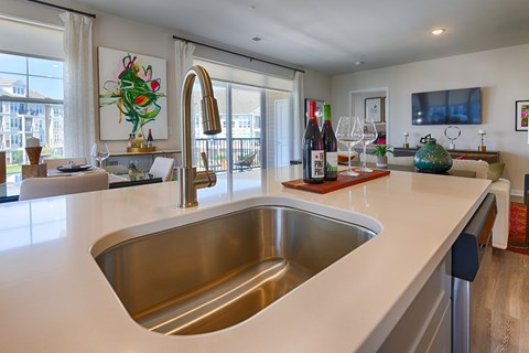 A modern kitchen with a stainless steel sink and a white countertop.