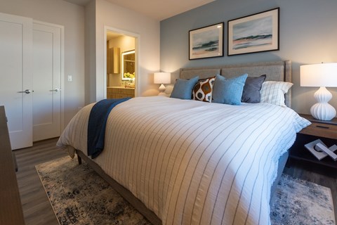 A bed with a white and blue striped comforter and a white nightstand with a lamp.