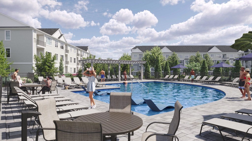a swimming pool with lounge chairs and tables in front of an apartment building