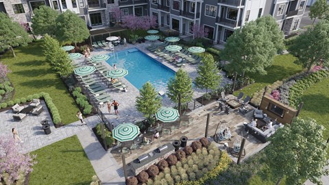 An aerial view of a pool surrounded by trees and umbrellas.