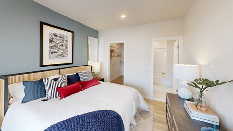 A bedroom with a bed, nightstand, and a painting on the wall.