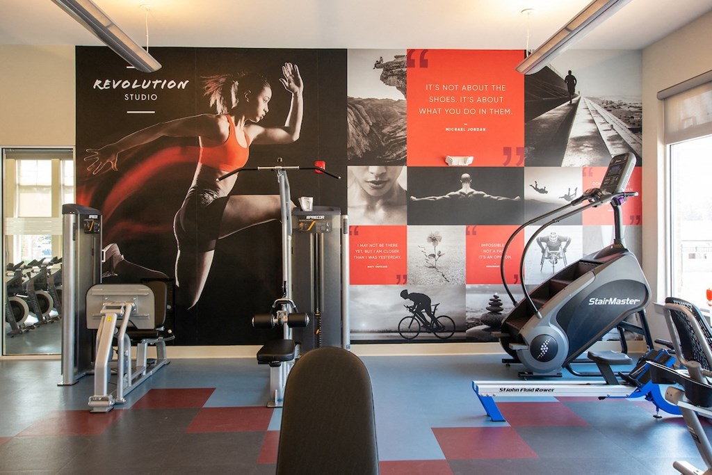 a gym with exercise equipment and a large mural on the wall