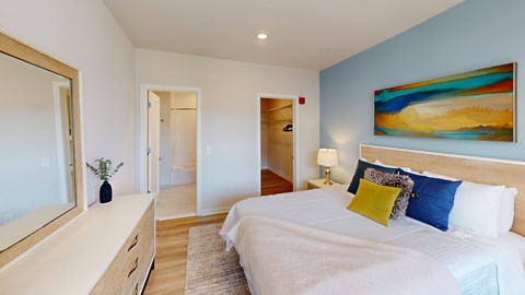 A bedroom with a large bed, a dresser, and a painting on the wall.