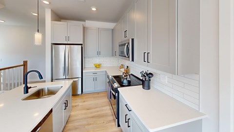 A modern kitchen with white cabinets and a wooden floor.