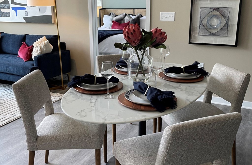 a dining room with a table and chairs and a couch in the background