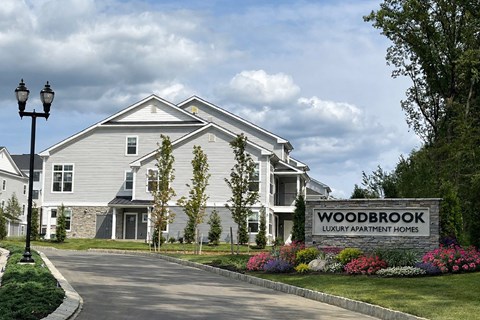 A sign in front of a house that says Woodbrook Luxury Apartment Homes.