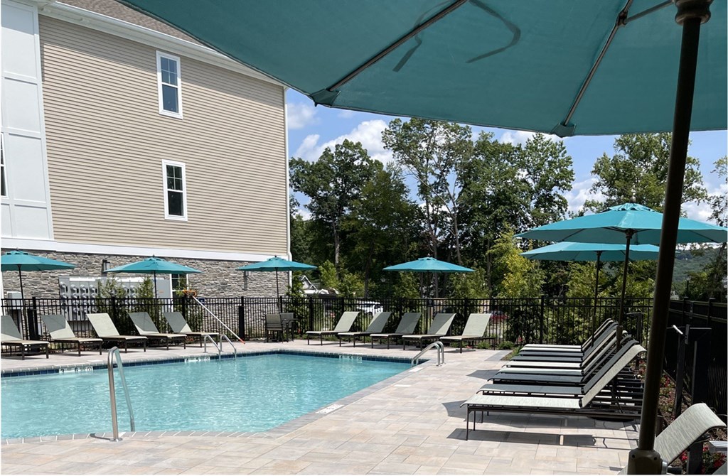 a swimming pool with chaise lounge chairs and umbrellas