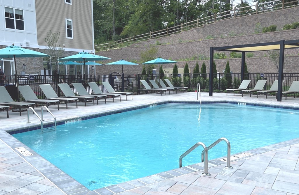 a swimming pool with lounge chairs and umbrellas