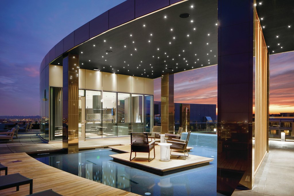 a living room with a pool and a city skyline at night