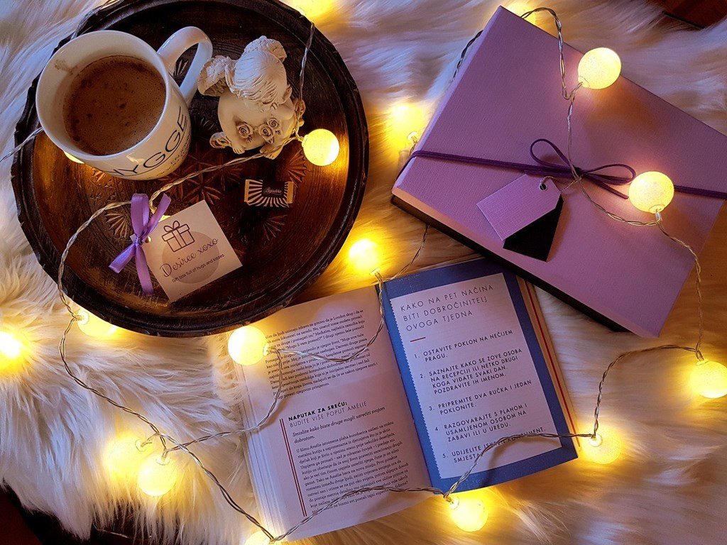 a book and a cup of coffee on a table with christmas lights