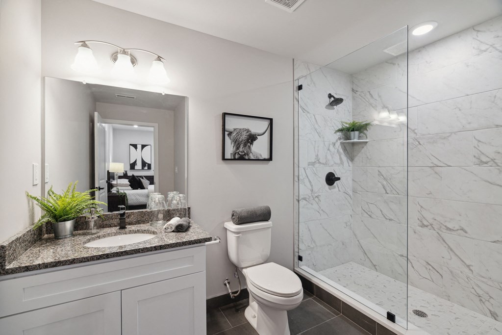 a bathroom with a toilet sink and shower with a glass door