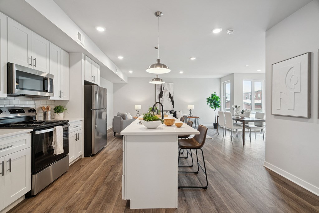 an open kitchen and dining room with white cabinets and stainless steel appliances