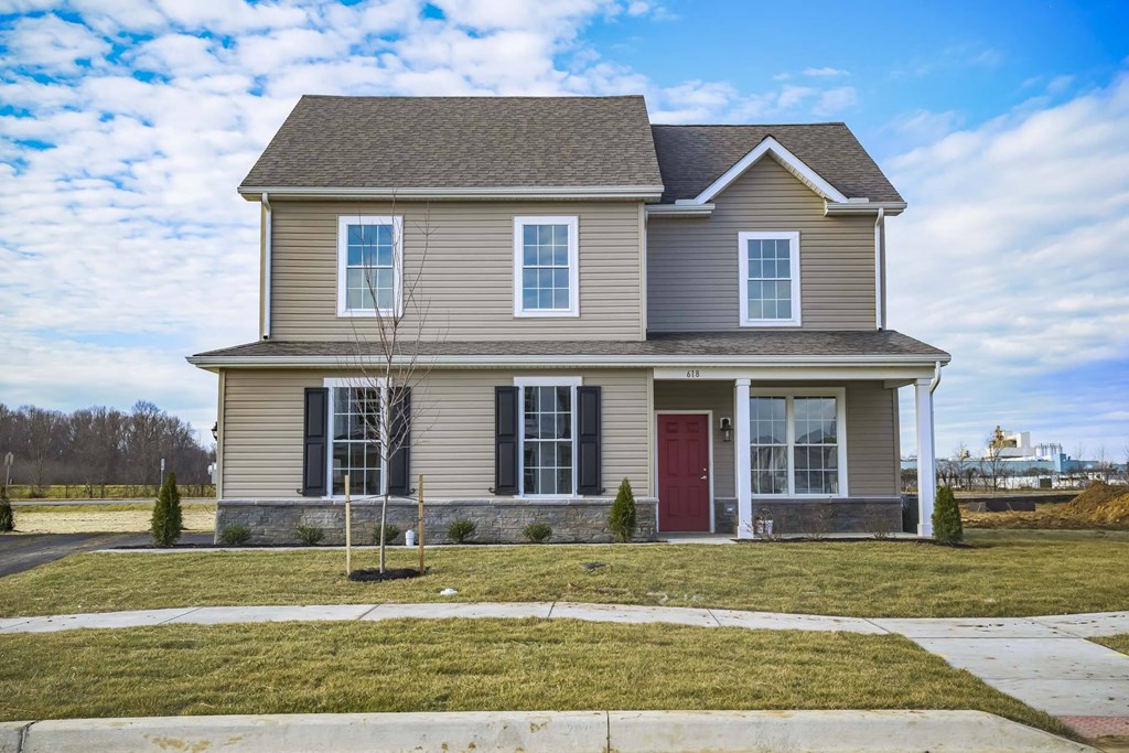 Exterior of tan 2 story cottage with lawn