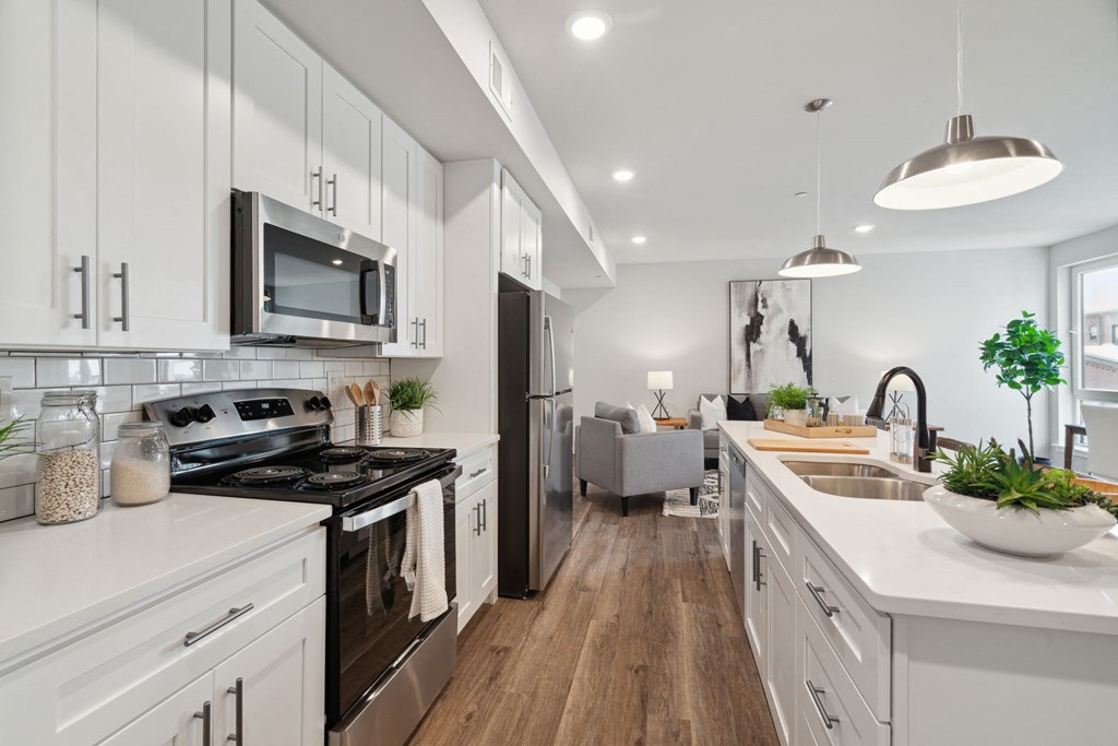 an open kitchen with white cabinets and stainless steel appliances and a living room