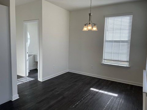 a living room with wood floors and a window and a chandelier
