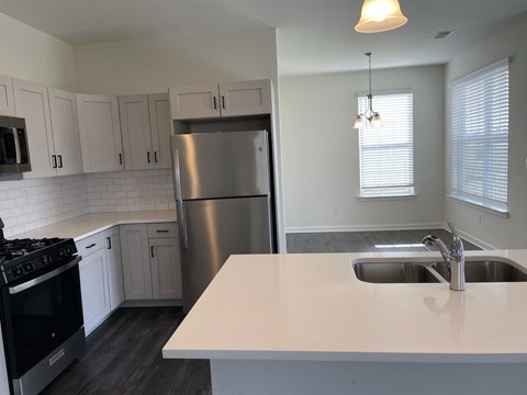 a kitchen with a white counter top and a stainless steel refrigerator