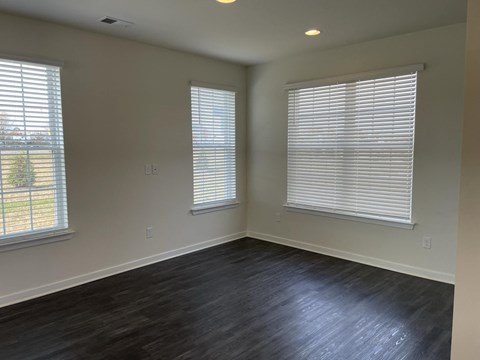 a living room with wood floors and two windows