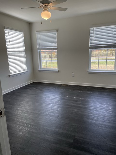 an empty room with wood floors and a ceiling fan