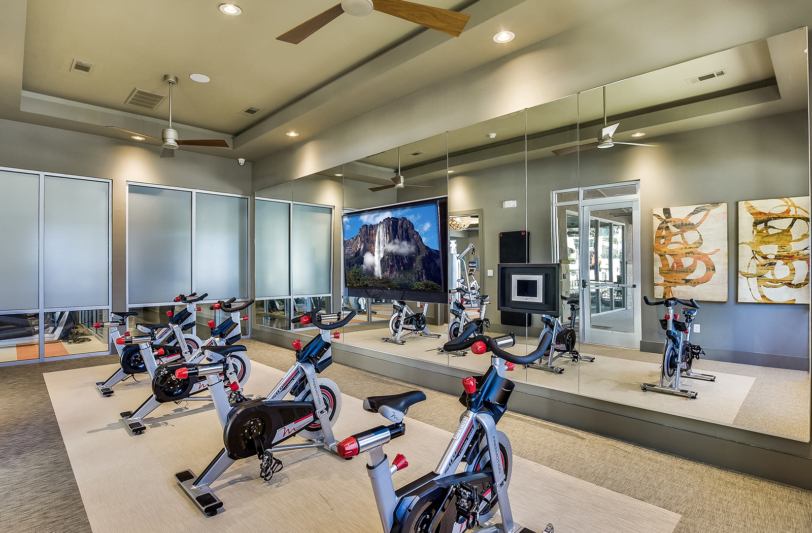 a gym with treadmills and exercise bikes and a tv