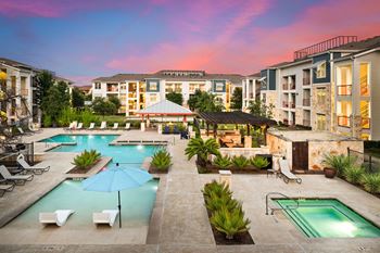 an outdoor pool with chairs and umbrellas at dusk