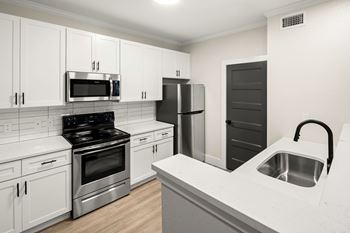 A kitchen with white cabinets and a black stove top oven.