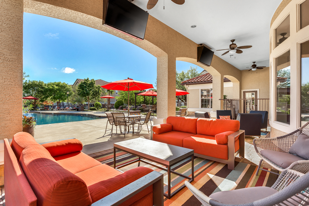 a patio with couches and tables and a swimming pool