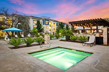a swimming pool with a building in the background at sunset