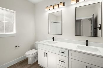 A white bathroom with a toilet, sink, and mirror.