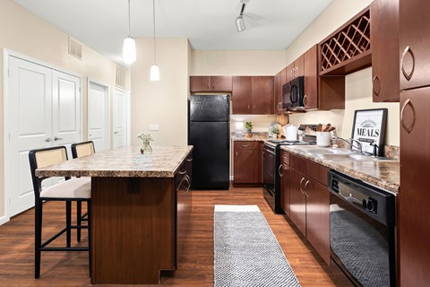 A kitchen with brown cabinets and a black refrigerator.