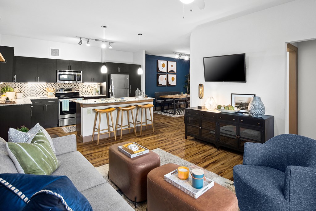 a living room with a kitchen with a bar and a tv